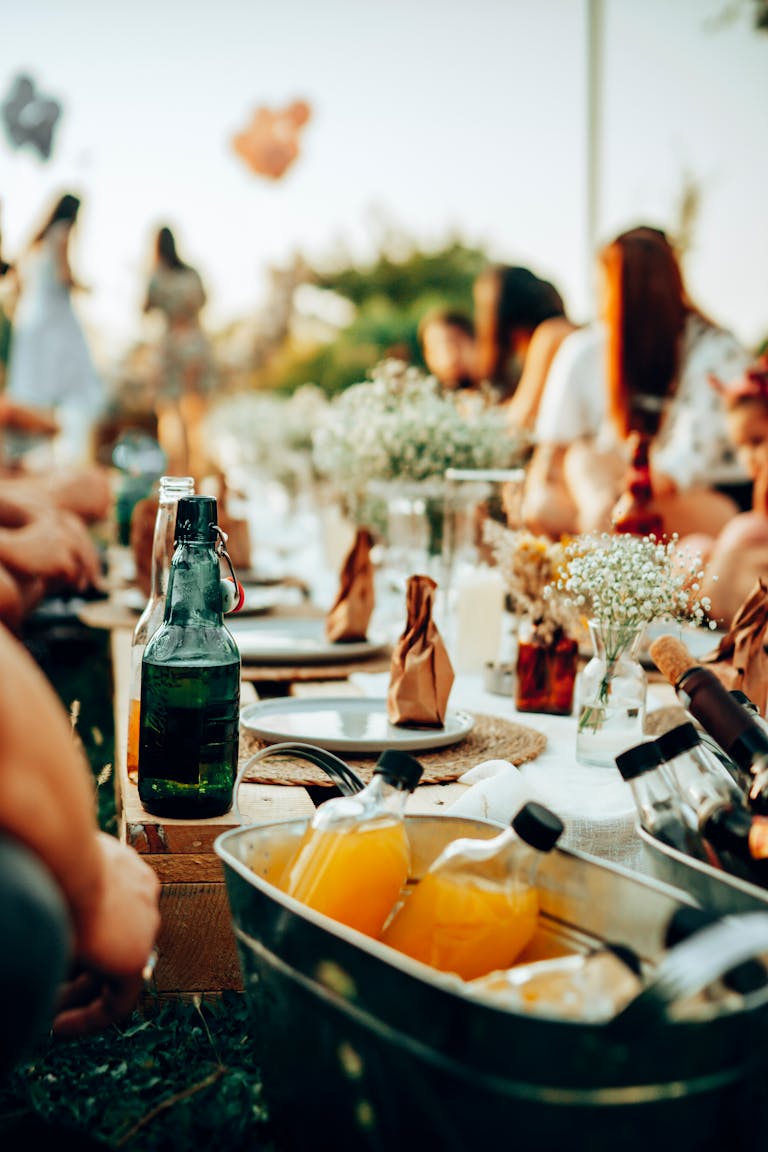 Vibrant outdoor gathering with drinks in a bucket and decorative flowers on table.